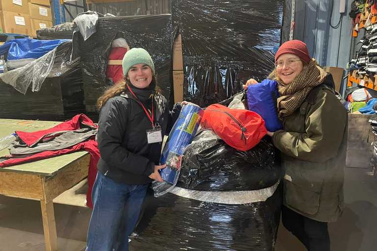 Two volunteers pose next to a large bag of humanitarian aid.