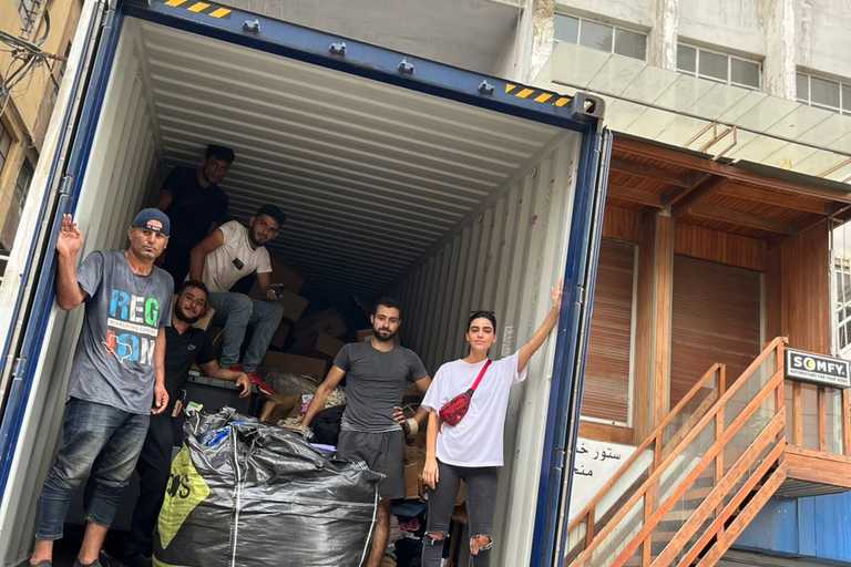 A group of people posing for a group picture inside a truck they have unloaded of humanitarian aid